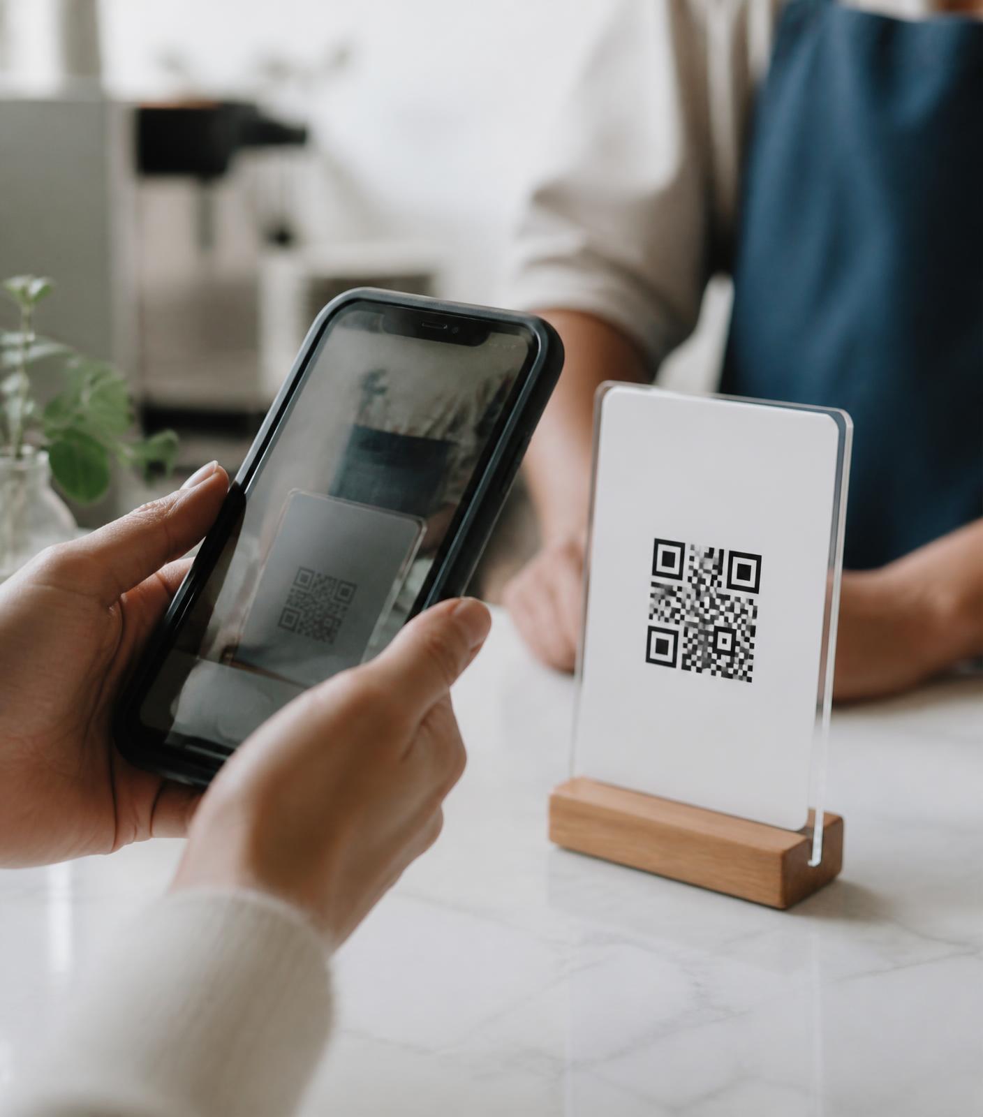 Cliente escaneando um QR Code de pagamento com o celular sobre o balcão